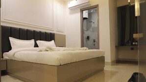 Habitació d'hotel moderna amb un llit gran, un armari encastat i una zona de banyera amb dutxa.