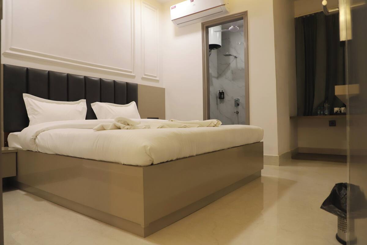 Una habitación de hotel moderna con una cama grande, un armario empotrado y zona de ducha.