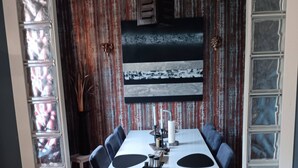 A dining area with a long table, chairs, and a decorative wall.