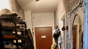 A hallway with a shoe rack, a mirror, a door labeled 'POST,' and a small table with items on it.