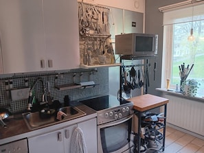 A kitchen with a microwave, stove, sink, and various utensils hanging on the wall. - Room-room in Apartment Within Walking di (Gothenburg)