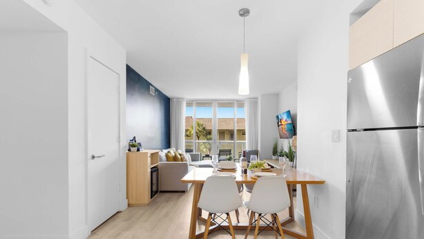 Una cocina moderna con comedor, ventanas amplias y un refrigerador de acero inoxidable.
