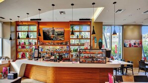 Un bar moderno con una barra curva, varias botellas y una pizarra de menú.