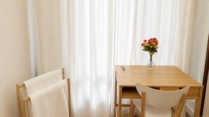 A room with a wooden table, a white chair, a towel rack, and a vase with flowers.