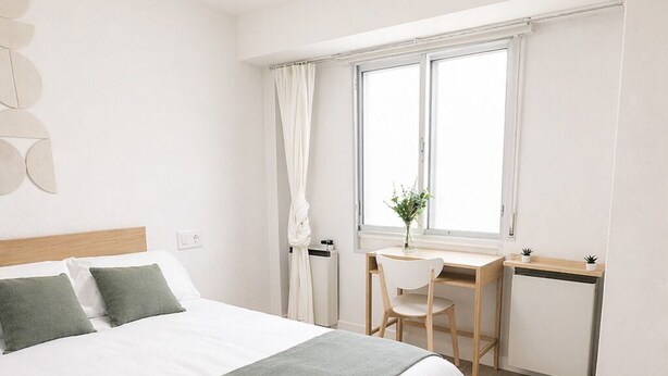 A bedroom with a bed, a desk, a chair, a radiator, and a window.