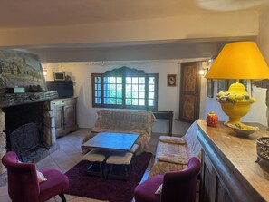 A cozy living room with a fireplace, a sofa, a table, and a lamp. - Charming house in Esparron de verdon, at the foot of the castle, overlooking the village. (Esparron-de-Verdon)