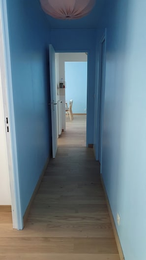 A hallway with blue walls and wooden flooring leading to a dining area with a table and chairs. - 3-room apartment with balcony between Anglet & Bayonne (Bayonne)