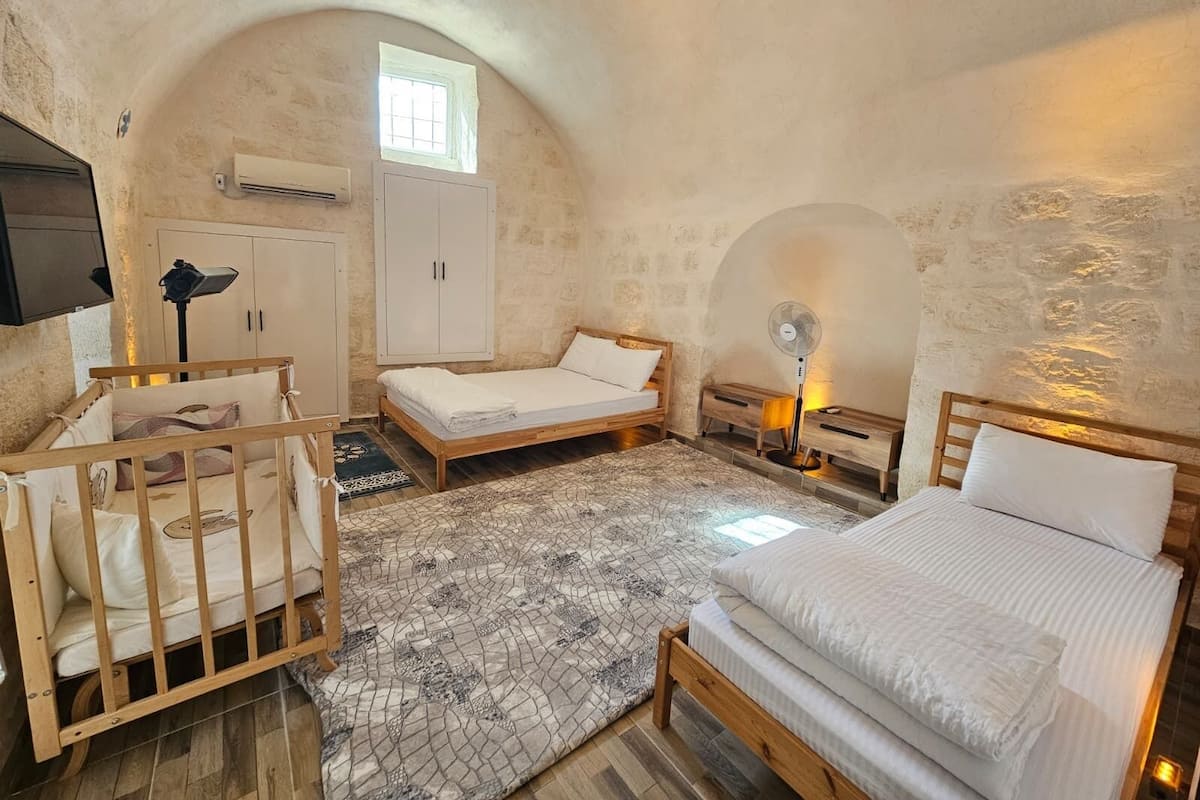 Ein gemütliches Schlafzimmer mit einem hölzernen Bett, einem kleineren Bett, einem Babybett, einem Schreibtisch und einem Kleiderschrank.