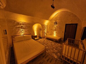 Une chambre à coucher avec un lit, une table de chevet, un banc et une porte.