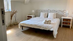A bedroom with a large bed, two bedside tables, a window, and a ceiling with a sloped design. - Cozy getaway at Obidos lagoon & ocean (Foz do Arelho)