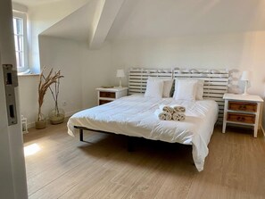 Une chambre à coucher avec un grand lit, deux tables de chevet, une fenêtre et un plafond à pente.