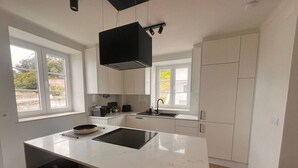 A modern kitchen with a large island, white cabinetry, and a black range hood. - Cozy getaway at Obidos lagoon & ocean (Foz do Arelho)