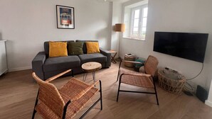 A living room with a sofa, two wicker chairs, a round coffee table, a floor lamp, a TV, and a framed picture on the wall. - Cozy getaway at Obidos lagoon & ocean (Foz do Arelho)