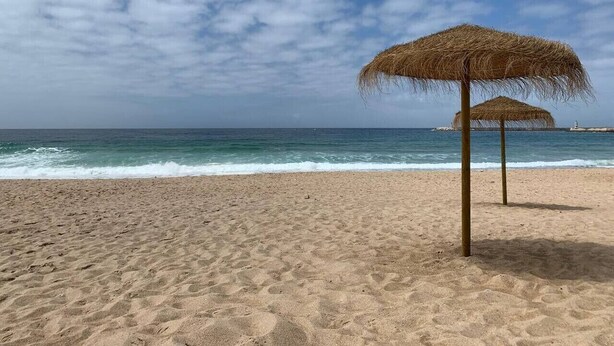 A beach with a thatched umbrella and calm sea. - Cozy getaway at Obidos lagoon & ocean (Foz do Arelho)