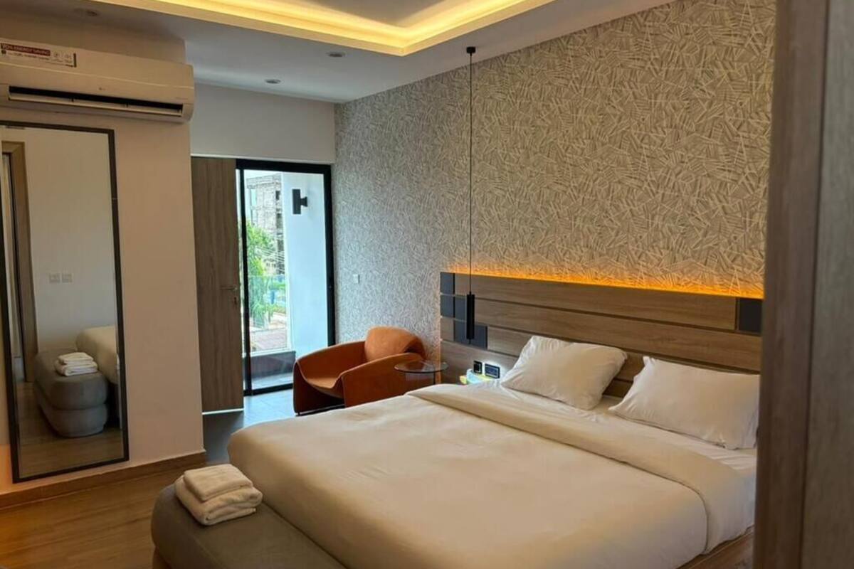 Habitación de hotel moderna con una cama grande, un espacio de descanso, aire acondicionado instalado en la pared y vistas a través de una puerta de cristal.