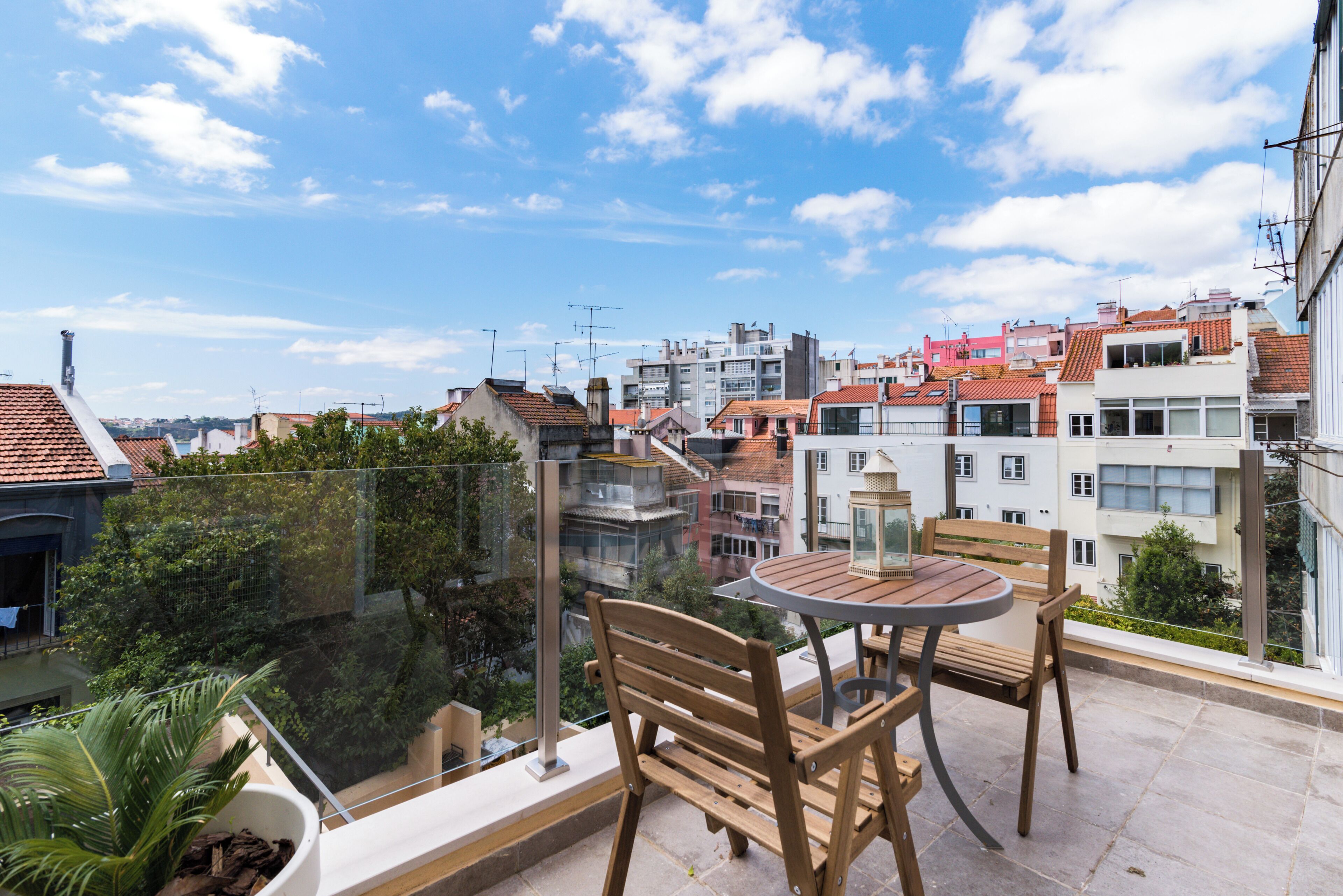 A balcony with a table and chairs, overlooking a residential area with various buildings.