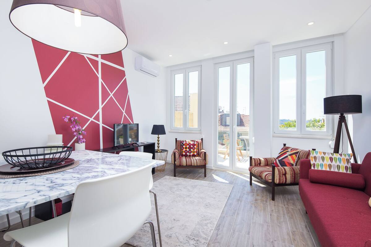 Un salon moderne avec une table en marbre, un canapé rouge, un fauteuil à rayures et une lampe sur pied.