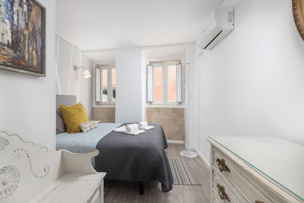 Une chambre à coucher comprenant un lit, une table de chevet, une commode et une fenêtre donnant sur un paysage agréable.