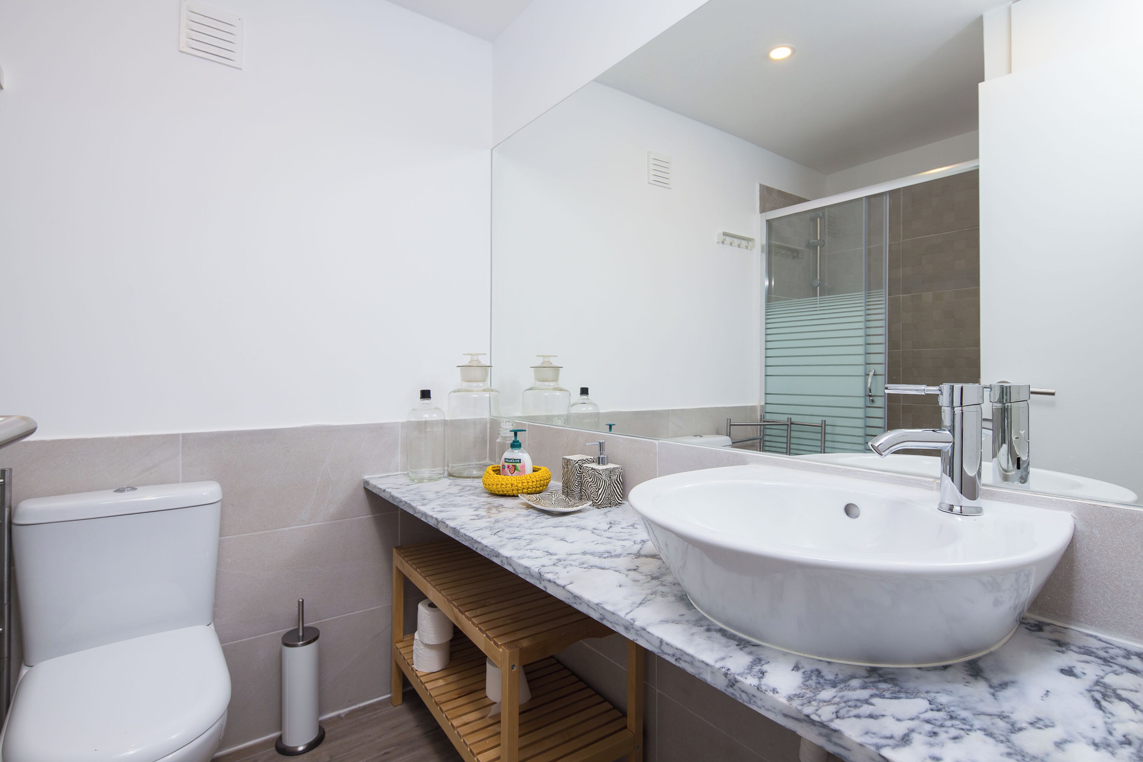 Un baño moderno con un lavamanos grande blanco, un inodoro y un espejo.