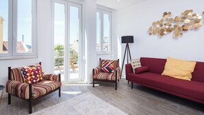 A modern living room with a red sofa, striped armchairs, and a patterned rug. - Designer Flats in Lapa (Lisbon)