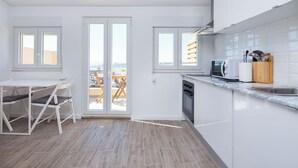 A modern kitchen with a dining area, large windows, and a view of the outside. - Designer Flats in Lapa (Lisbon)