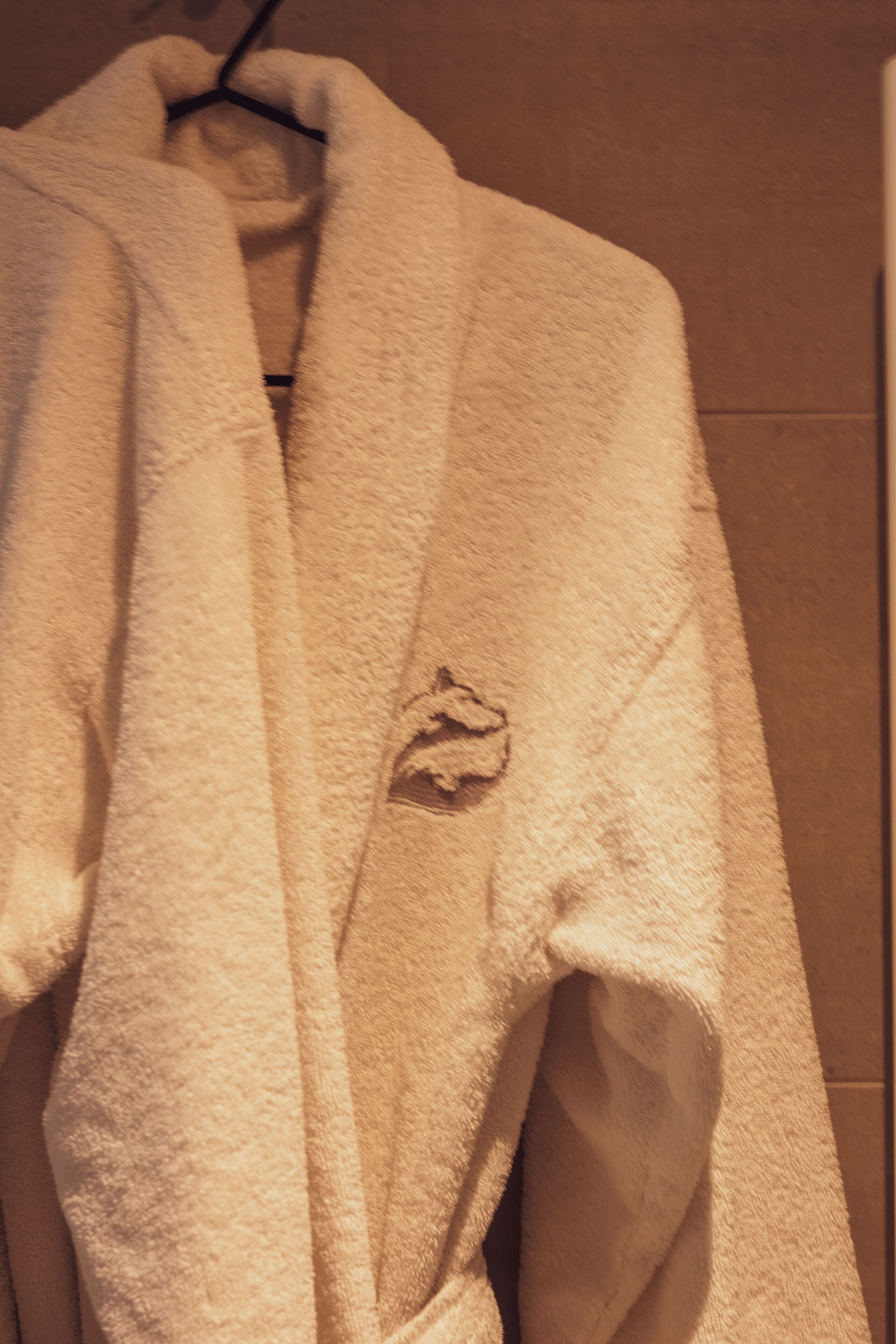 A white bathrobe hanging on a black hanger.