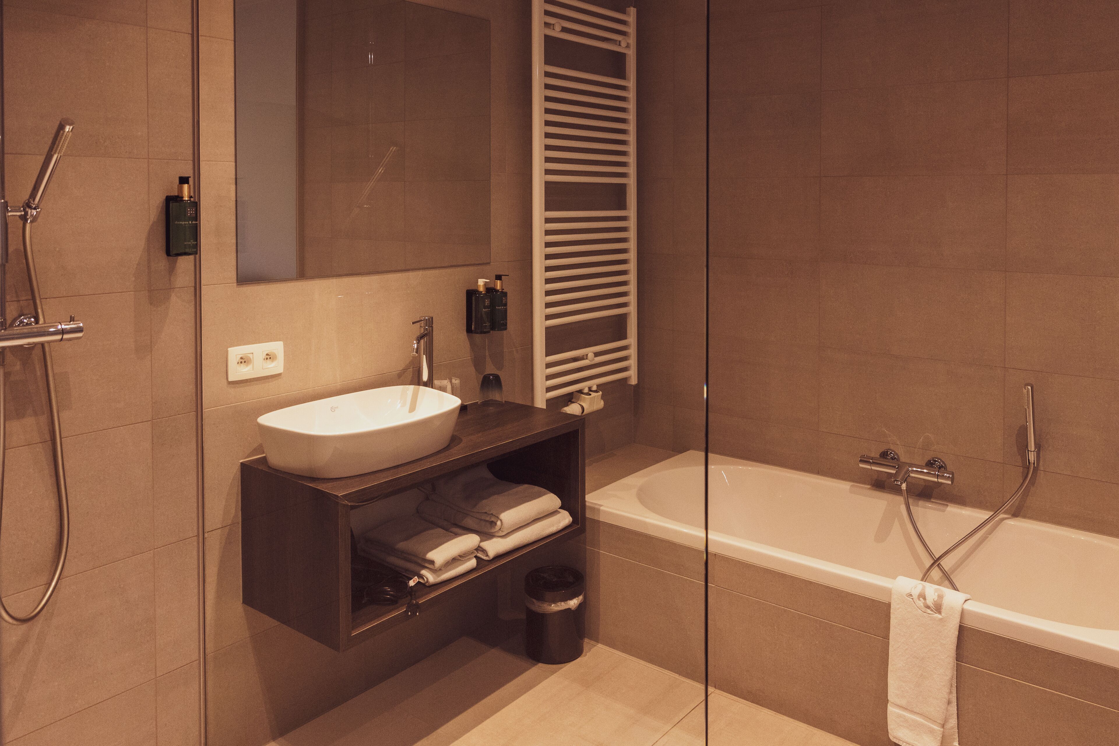 A modern bathroom with a bathtub, a sink, a mirror, and a towel rack.