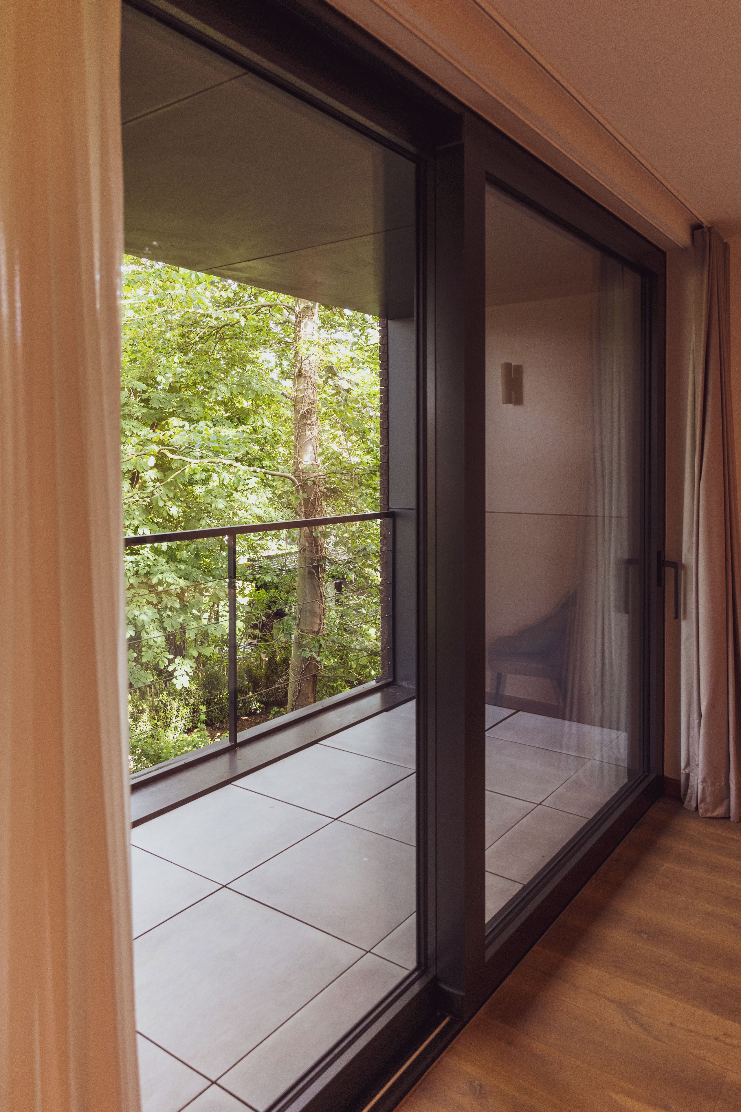 A room with a sliding glass door leading to a balcony with a view of trees.