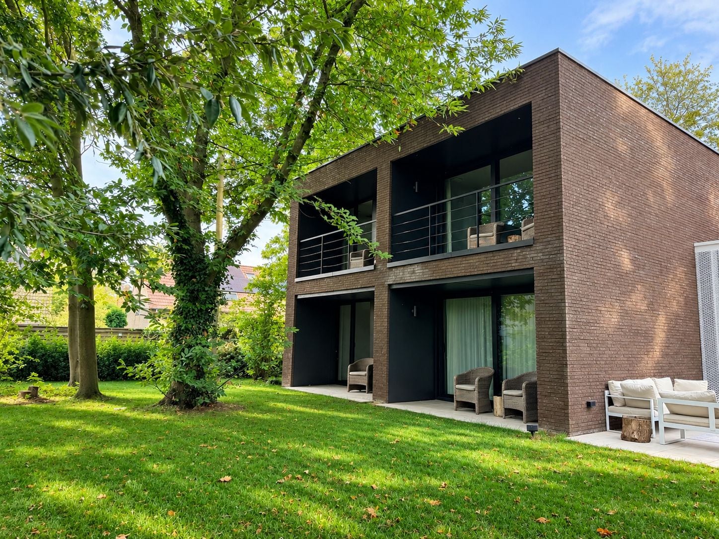 A modern two-story building with a brick facade, large windows, and outdoor seating.