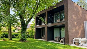 A modern two-story building with a brick facade, large windows, and outdoor seating.