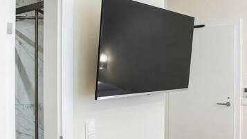 Habitación con televisión de pantalla plana en la pared, una puerta y suelo de madera.