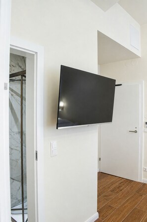 Habitación con televisión de pantalla plana en la pared, una puerta y suelo de madera.