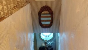 A staircase with a wooden handrail, a wall with a textured pattern, and a mirror above the steps. - São Pedro Suítes (Faro)