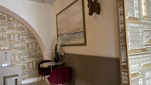 A room with a cityscape wallpaper, a framed painting, a wooden headboard, and a small table with chairs. - São Pedro Suítes (Faro)