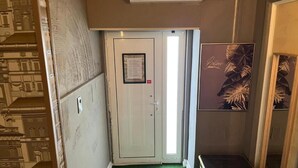 A narrow hallway with a green carpet, a white door with a notice, and a framed artwork on the wall. - São Pedro Suítes (Faro)