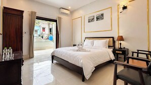 A hotel room with a bed, bedside table, lamp, and a view of the outside. - Rose Wood Cat Ba Villa (Hai Phong)