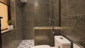 Un baño moderno con ducha, inodoro y baldosas de suelo estampadas.