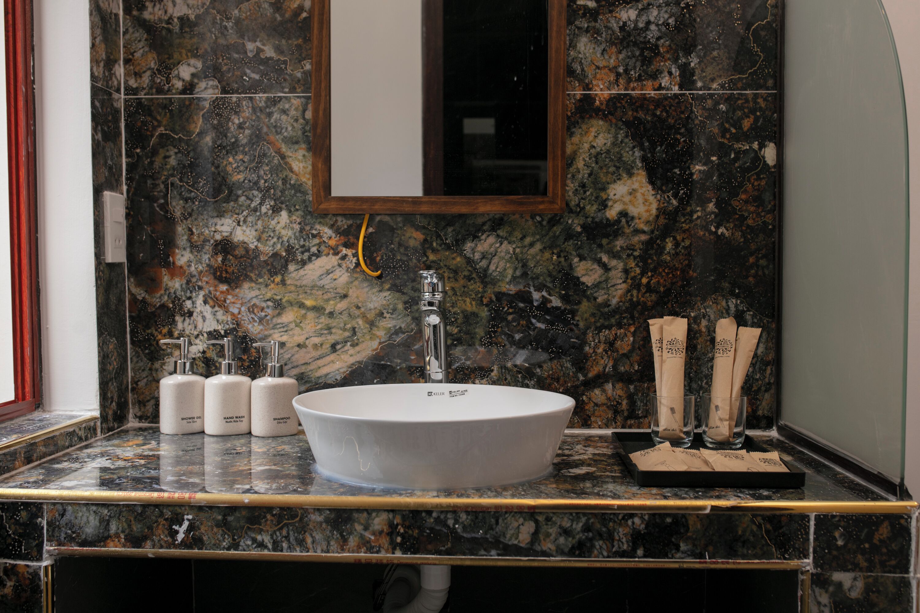 Un baño con lavamanos de mármol, espejo y artículos de tocador.