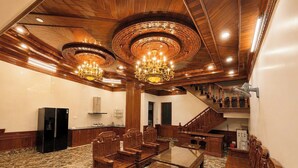 A spacious room with a marble floor, wooden furniture, a chandelier, and a staircase. - Rose Wood Cat Ba Villa (Hai Phong)