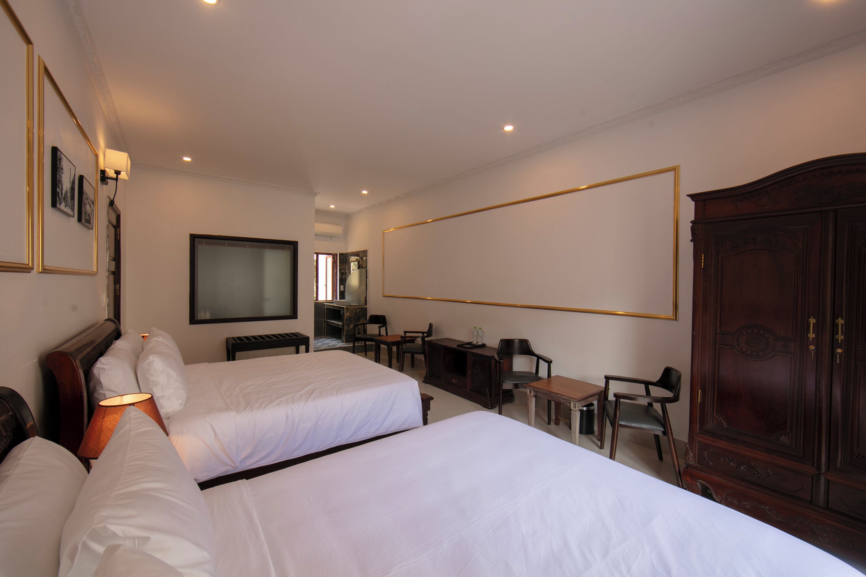 A hotel room with two beds, a desk, a chair, a television, and a wardrobe.