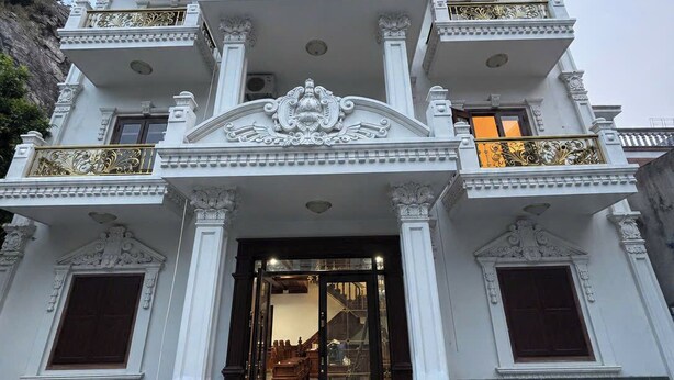 A multi-story building with a grand entrance, ornate balconies, and a staircase leading to the door. - Rose Wood Cat Ba Villa (Hai Phong)