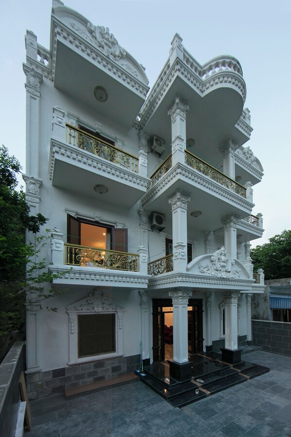 A multi-story building with ornate architectural details, including columns and balconies. - Rose Wood Cat Ba Villa (Cat Hai)