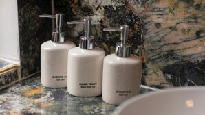 Tres botellas de artículos de tocador sobre una encimera de mármol.
