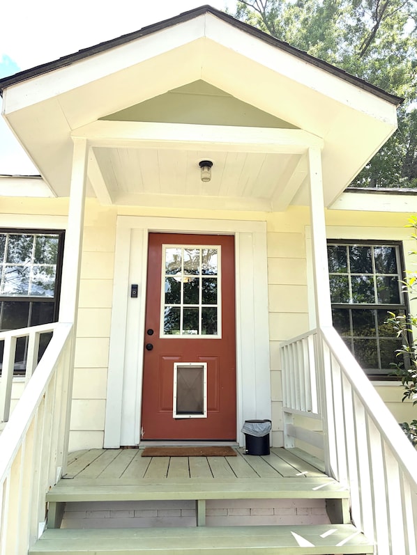 A house with a front porch, a brown door, and a small window above the door.