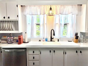 A kitchen with a white countertop, a black faucet, and a window with sheer curtains. - The Cozy Cottage: 3-bedroom/2-bath home in the heart of Lucedale (Lucedale)