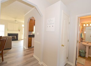 A hallway leading to a kitchen with wooden cabinets and a dining area with a table and chairs.
