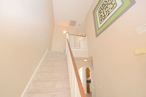 A carpeted staircase with a wooden handrail, a white door at the bottom, and a framed picture on the wall. - Coastal Getaway~Large Clean-n-Cozy 3Bdrm Home (Virginia Beach)