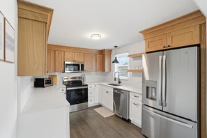 A modern kitchen with wooden cabinets, stainless steel appliances, and a built-in microwave.