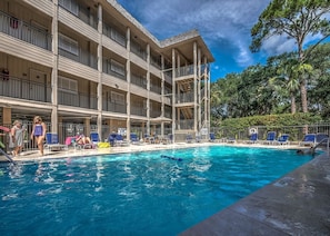 Ein Hotel mit Schwimmbad, mehreren Balkonen und einer überdachten Liegebereich.