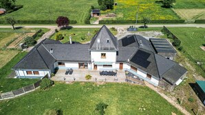 A large house with a sloped roof, a covered patio, and a fenced yard. - Holiday Home "Gîte du Tronquoy" with Private Terrace, Garden and Wi-Fi (Aix-en-Ergny)
